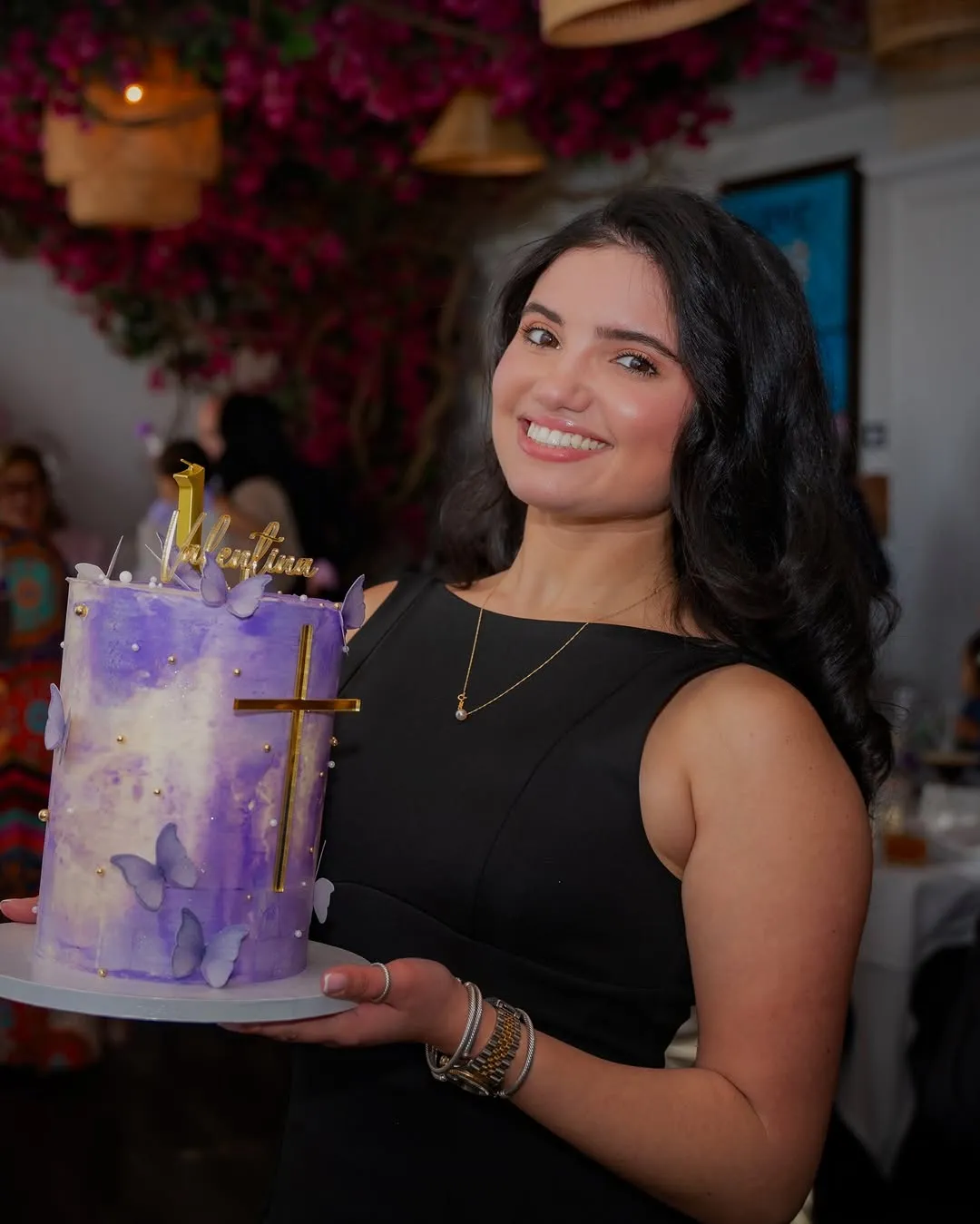 Ari smiling and holding a purple butterfly cake