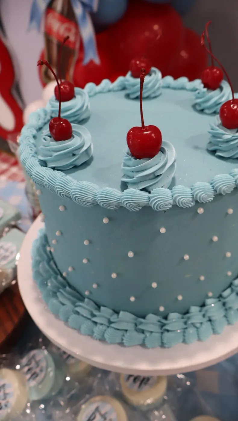 Light blue vintage piped cake topped with cherries