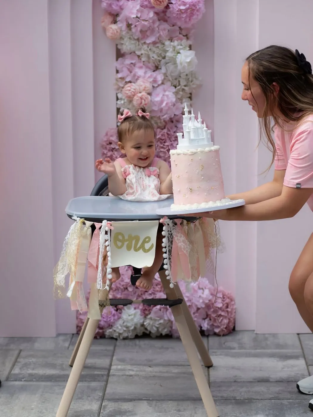 Baby in a high chair with a pink castle cake