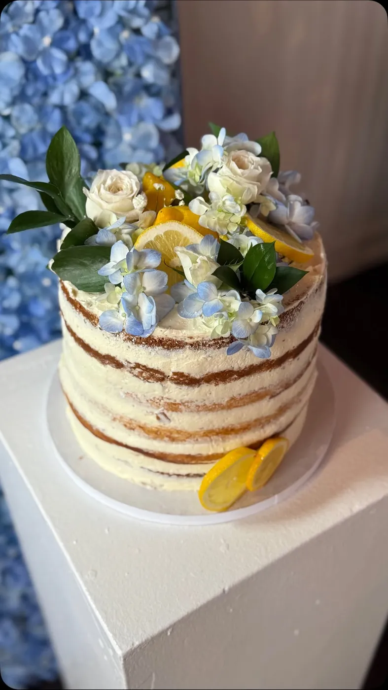 Naked layer cake topped with white roses and lemon slices